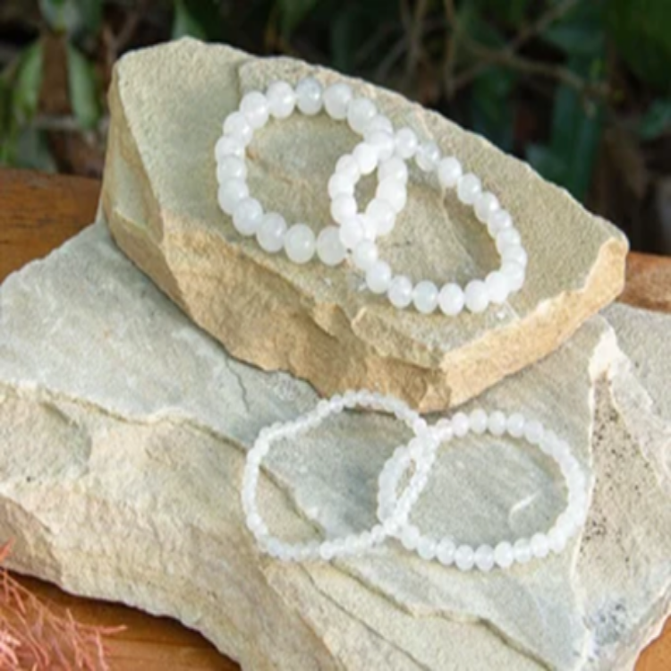 White Jadeite beaded bracelets with silver accents displayed on natural stones.