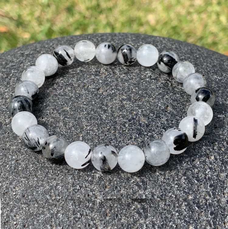 White Rutilated Quartz beaded bracelet on gray stone background.